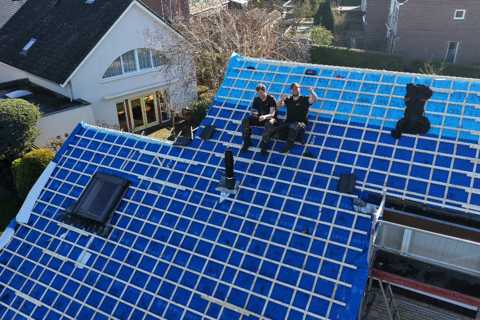 Dakdekker aan het werk tijdens een dakrenovatie in Warmond