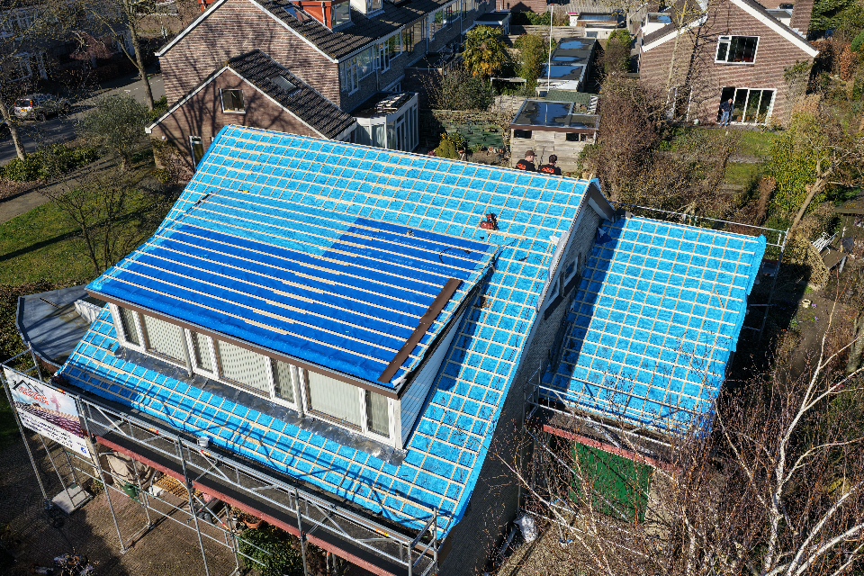 Dak tijdens renovatie met beschermende blauwe dakfolie in