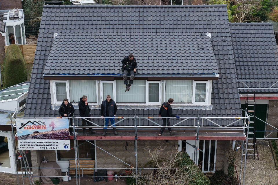 Dakdekkers aan het werk op een pannendak in Warmond