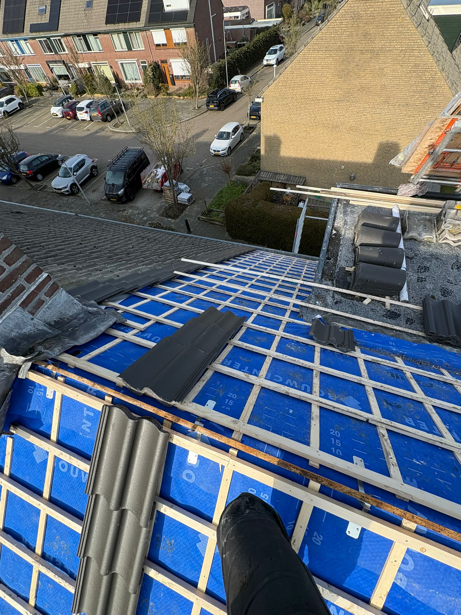 Woning tijdens dakrenovatie met blauwe dakfolie in Lisse